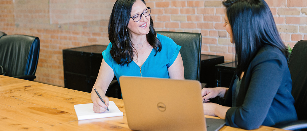 Two women sitting at desk with laptop