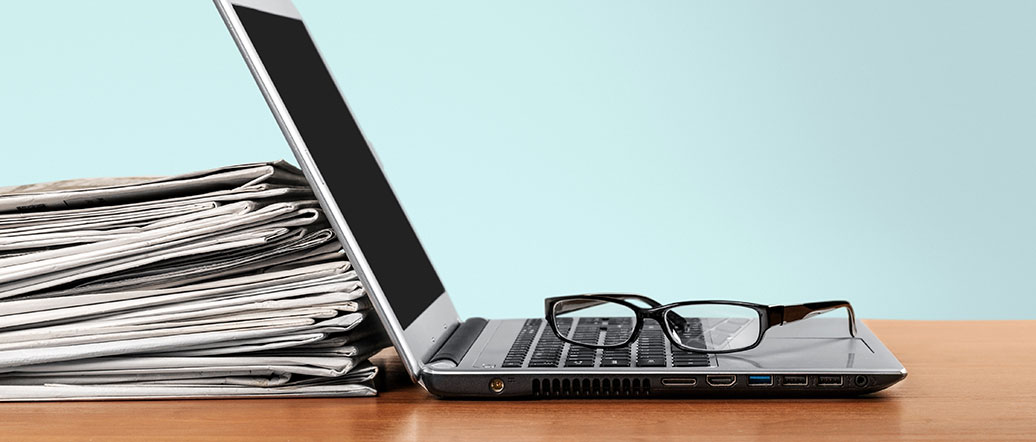 laptop and newspapers on desk